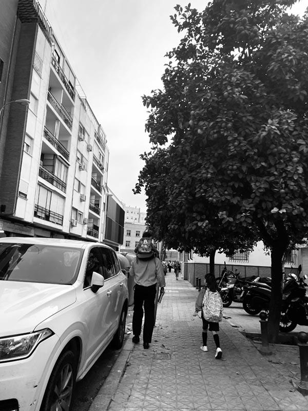 Black and white photo of father walking children to school.